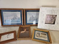 Five framed vintage pictures on a wall: two ship prints, dog portrait, interior scene print, and old photo in decorative frame.