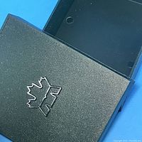 Black hard plastic protective case with embossed maple leaf logo on the lid.