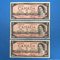 Three 1954 $2 Canadian banknotes front view showing serial numbers and Queen Elizabeth II portrait.