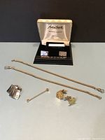 Full lot showing two gold-tone watch fobs with chains, a pair of silver-tone cuff links with a wavy design, a pearl-tipped shirt pin, and a boxed Forstner sterling silver tie clip and cuff links set.