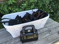 View of white wicker basket containing multiple purses, including one outside the basket.