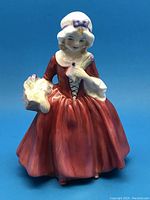 Front view of Lavina figurine by Royal Doulton in a red dress with basket and bonnet.