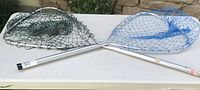 Image showing the two fishing nets crossed, green fabric net on left with extendable handle, blue nylon net on right with fixed handle.