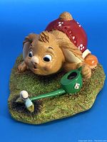 View of Pendelfin Alfoe bunny lying on mossy base with green watering can and mushroom showing front-left perspective.