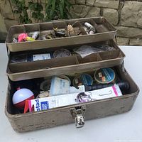 Open tackle box showing compartments with various fishing lures and gear inside