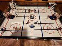 Top-down view of table hockey game showing rink surface, player rods, nets and electronic goal boxes