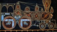 Close-up photo showing the detailed construction of a train artwork made using wire, string, needles, nuts, bolts, and can tabs.