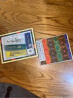 Overview of the open box with ink sticks and accessories laid out and closed box next to it on wooden floor