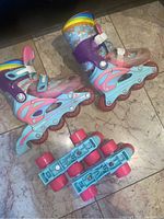 Pair of colorful girls inline skates and a pair of blue and pink quad roller skates on tile floor