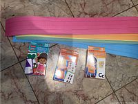 Three Fisher-Price Little People educational flash card packs on the floor with colorful writing strips above them in pink, yellow, orange, green, and blue.