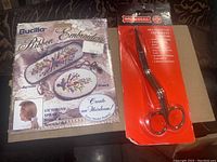 Photo showing Bucilla ribbon embroidery kit with Victorian Spray design for brooch and barrette along with Mundial embroidery scissors in original packaging.