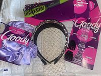 Full view of all items in the lot including the satin bonnet with original packaging, the vented brush, the pack of small clips, and three headbands.