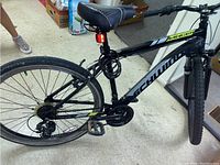 Side and rear view of Schwinn Ranger 26 inch mountain bike showing rear derailleur, pedals, seat with cable lock, and black frame with yellow and white markings.
