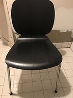 Front view of the dark brown/black curved seat and backrest with chrome legs on tiled floor.