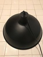 Top view of black matte conical ceiling light fixture showing smooth surface and integral loop at top for cord attachment.