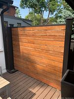 Front side view of cedar wood outdoor partition showing finished wood slats and black metal wrapped 4x4 posts.