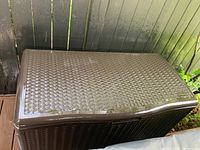Closed view of the dark brown wicker-pattern plastic storage box showing top and front sides.