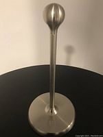 Full view of chrome paper towel holder showing the rounded finial at the top and brushed metal base.