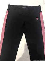 Black leggings with pink side stripes laid flat showing the front and waistband area