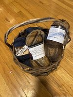 Photo showing a woven basket containing two variegated bulky yarn balls and other yarn balls partially visible