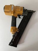 Full side view of Stanley Bostitch 15 Gauge Pneumatic Nailer showing yellow housing and black handle with nail clip.