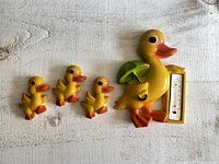 Set of four chalkware duck figurines; one large with thermometer, three small without thermometer.