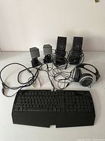 Computer accessories: black wired keyboard, wired headphones, two small generic speakers with power adapters