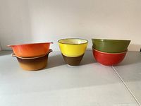 Side view of stacked colorful vintage mixing bowls including orange, yellow, olive green, red