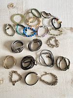 Full lot view showing various beaded, metal chain, fabric wrap, and bangle bracelets arranged on a light surface