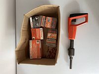 Wide view of all items including Remington nailer and cardboard box containing boxes and loose nails/charges