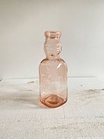 Full view of the vintage light pink Brookfield baby top quart milk bottle showing overall shape and coloration.