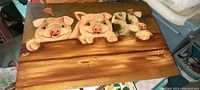 Photo showing front of solid slate piece with hand-painted design of three pigs leaning over a wooden fence.