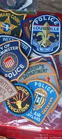 Photo showing close-up of multiple police and sheriff department patches stacked together, featuring detailed embroidery and various official insignias.