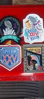 Top view showing all four original 1990s Super Bowl jacket patches, colorful designs featuring different Super Bowls XVIII, XXIV, XXV, and XXVII.