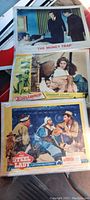 Three vintage movie lobby cards stacked, showing titles 'The Money Trap' on top, 'Bullwhip' partially visible under it, and 'The Steel Lady' at the bottom.