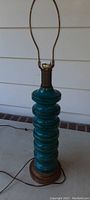 Full view of tall floor lamp showing deep blue/aqua glass stacked design with goldtone base and metallic harp for a lampshade