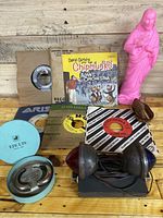 Overview of lot showing multiple 45 RPM vinyl records with sleeves, pink statue, baby doll, wine ring, and beehive diodes.