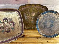 Three vintage gilded trays in varied shapes and sizes, showing overall design and condition