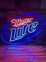 Lit Miller Lite neon sign showing red, blue, and white neon tubing illuminated against wooden wall background.