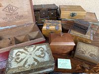 Photo of set of 10 old wooden boxes arranged on table showing various sizes, carved and decorated boxes.