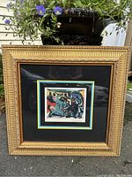 Framed colorful Picasso print reproduction with detailed gold frame and matting, outdoor photo showing overall piece