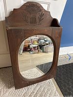 Front view of rustic wooden medicine cabinet with carved top and arched mirror