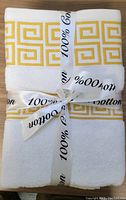Front view of folded towel set tied with 100% cotton ribbon, showing yellow geometric border design