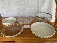 Front view of assorted serving dishes and plates including glass and white ceramic pieces on wooden surface