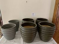 Photo of six ceramic planter pots, four larger and two smaller, showing ribbed textured exterior and muted brownish-gray color.