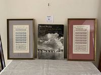 Full view of the two framed sheet music pieces and the Prague travel book arranged side by side on a table
