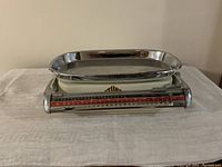 Front view of the vintage metric kitchen weight scale showing chrome tray and red measurement scale.
