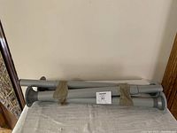 Four grey telescopic metal table legs bundled together with brown tape, showing circular mounting plates and folded height.