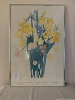Full view of framed floral print artwork showing bouquet of yellow, pink, blue flowers and green leaves with visible sun faded colors and metal frame.