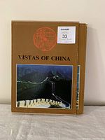 Front view of "Vistas of China" travel book with protective cover, showing minor wear on the back cover.